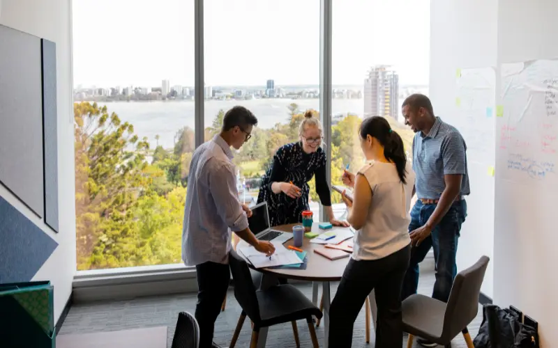 workflow4biz image of a group of workers around a table standing and talking
